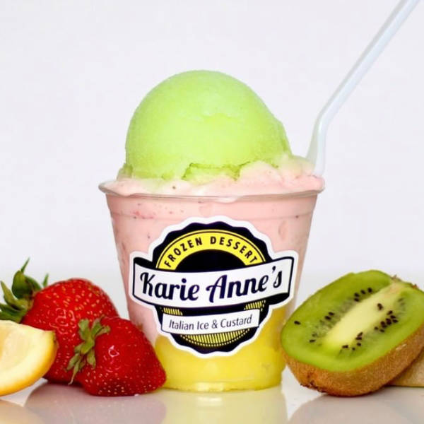 a gelati with pink custard and yellow and green Italian ice, with strawberries and kiwi in the background