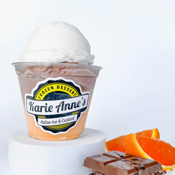 a gelati with chocolate custard and orange and white italian ice, with some orange slices and chocolate pieces to the side
