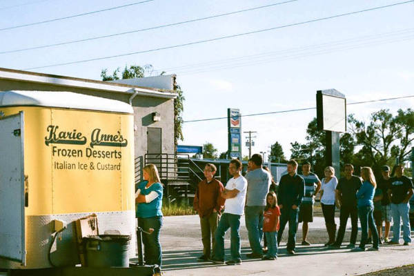 a line of people waiting to order from a Karie Anne's Frozen Desserts truck